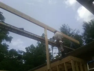 Carpenter setting a ridge beam over a new addition frame — Ice Dam Removal by Roofing Brothers in Lima