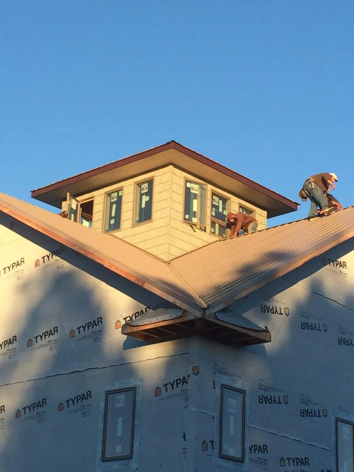 Roofers working around a rooftop cupola on a new metal roof at sunset — Roof Waterproofing in Lima by Roofing Brothers